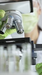 Close up of green gloved hands of a scientist adjusting a microscope in a laboratory, emphasizing the significance of scientific research and analysis. Medicine, healthcare and science concept