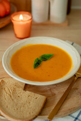 Plate of hot pumpkin soup and a slice of dark bread on the table. Warm autumn food. Immunity.