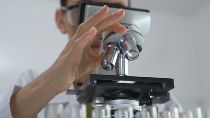 Female scientist analyzing test samples under microscope in contemporary research environment of laboratory. Medicine, healthcare and science concept