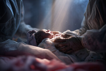 Newborn being gently cleaned by a nurse in a sterile environment after delivery during a quiet moment in the delivery room