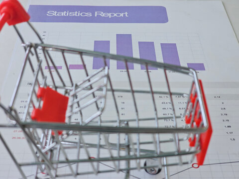 Shopping cart placed on a statistics report with graphs and data analysis details - Powered by Adobe