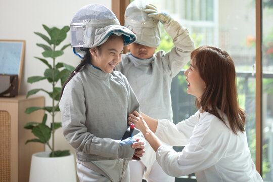 A mother encourages her athlete daughter and son before they go out to compete in fencing.