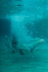 Artistic underwater capture of a woman surrounded by bubbles, gracefully moving in the pool.