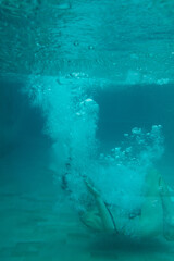 Abstract underwater shot of a woman diving into the pool with splash and motion bubbles