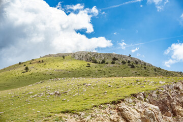 Landscape of green meadows between mountains, with a blue sky with clouds.