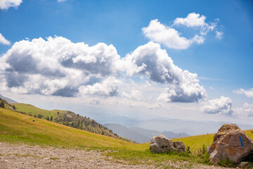 Landscape of green meadows between mountains, with a blue sky with clouds.