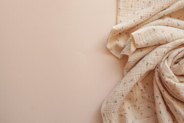 Crinkled beige muslin fabric with tiny floral print, softly draped on a neutral background. Light,...