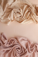 Two rolled muslin fabrics — one beige with small floral print and one dusty pink — laid on a...