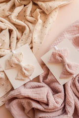 Soft cotton baby headbands with bows displayed on textured fabric in pastel pink and beige tones....