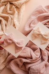 Pastel pink and cream baby headbands with fabric bows on cards, displayed on soft textured cloth....
