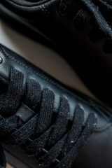 Close-up macro shot of black leather sneaker laces, showing detailed texture of fabric and...