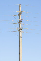 Power lines stretching across a clear blue sky on a concrete pole