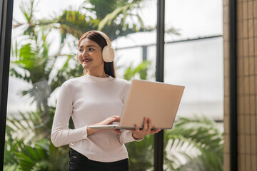 Young asian freelancer working remotely using laptop and headphones