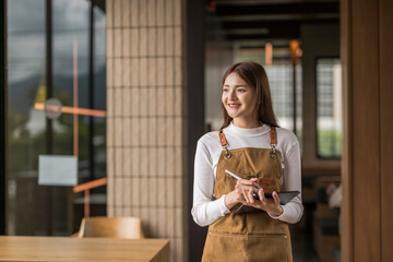 Smiling waitress taking orders using digital tablet in modern cafe