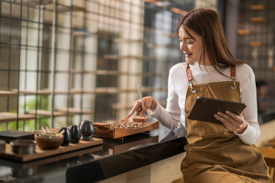 Barista managing her business using a tablet and checking coffee beans