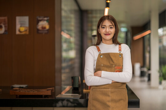 Asian female barista smiling with arms crossed in coffee shop