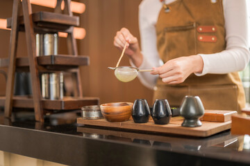 Barista filtering matcha tea in modern cafe: preparation of traditional japanese beverage