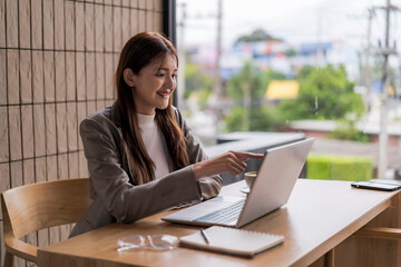 Businesswoman working on laptop in cafe, enjoying coffee and city view