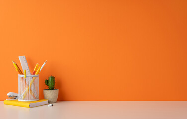 Colorful and modern workspace featuring a pencil holder, cactus plant, and orange wall