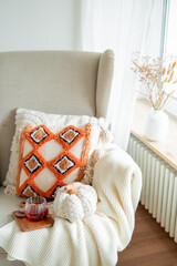 Cup of hot spiced tea, chocolate chip cookies, autumn decor with pumpkins, a cozy chair with a...