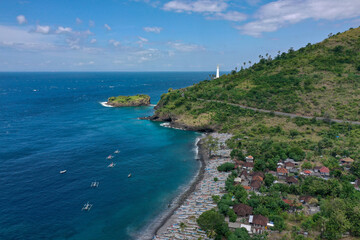 Drone Panorama of Balinese Fishing Bay with White Boats, Forested Hills, and Distant Lighthouse