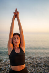 Woman practicing yoga pose near shoreline during golden sunset, embodying tranquility