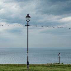 Two street lamps by the sea under overcast sky