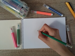 The girl prepares to take notes in a notebook, using multi-colored markers for convenience