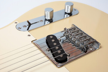 Six-string electric guitar, with a cream-colored wooden body and chrome-plated fittings.