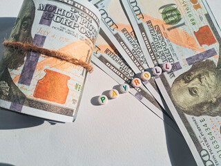 Close-up of rolled US dollar bills with beads spelling 