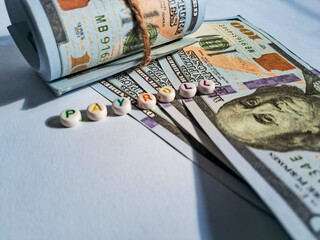 Close-up of rolled US dollar bills with beads spelling 