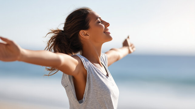 Joyful woman with outstretched arms enjoys the sunshine and fresh air on a beach.