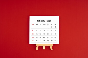 Calendar page for January 2026 with wood easel on a dark red background.