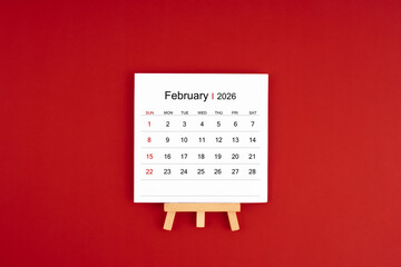 Calendar page for February 2026 with wood easel on a dark red background.