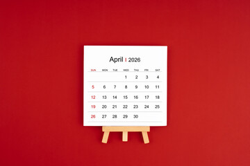 Calendar page for April 2026 with wood easel on a dark red background.