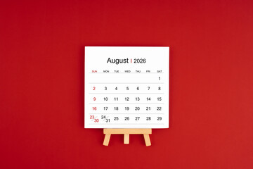 Calendar page for August 2026 with wood easel on a dark red background.