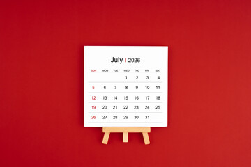 Calendar page for July 2026 with wood easel on a dark red background.