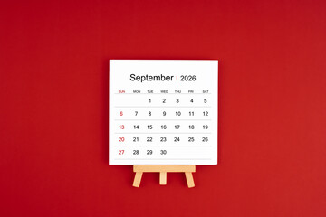 Calendar page for September 2026 with wood easel on a dark red background.