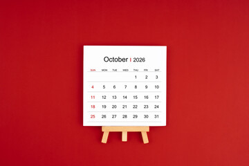 Calendar page for October 2026 with wood easel on a dark red background.