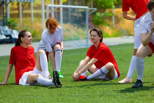 Women football players relaxing on the field after practice session. Concept of diverse female youth in shared training, focus on team effort and wellness in inclusive sports space. - Powered by Adobe