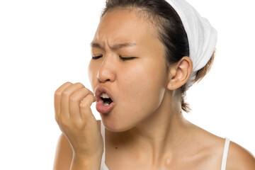 Asian woman checking her breath by exhaling into hand, skincare studio shot on white background.