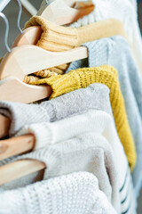 Warm cozy clothes on hangers. Knitted autumn sweaters. Home organization.