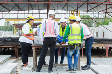 Group of engineers and supervisors working together at concrete manufacturing plant, focused on...