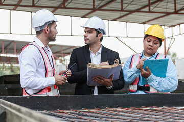 Three construction professionals including civil engineers and site staff are discussing blueprints...