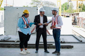 Three construction professionals including civil engineers and site staff are discussing blueprints...