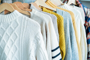 Warm cozy clothes on hangers. Knitted autumn sweaters. Home organization.