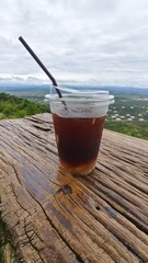 Refreshing iced coffee on wooden table outdoors.