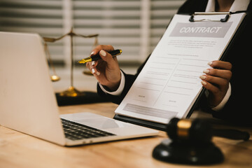 Close-up of a lawyer gesturing during a consultation at a desk with a laptop, gavel, documents, and scales of justice, symbolizing legal discussion and decision-making.