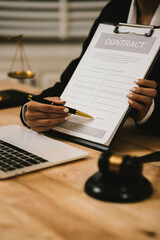 Close-up of a lawyer gesturing during a consultation at a desk with a laptop, gavel, documents, and...