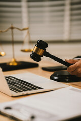 Close-up of a lawyer gesturing during a consultation at a desk with a laptop, gavel, documents, and scales of justice, symbolizing legal discussion and decision-making.